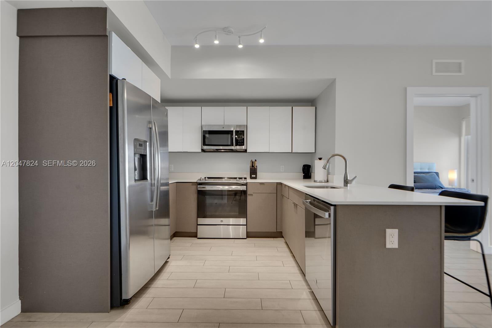 A modern kitchen features stainless steel appliances, white upper cabinets, and a breakfast bar — 321 NE 26th St # 806, Miami FL 33137, MIAMI, FL