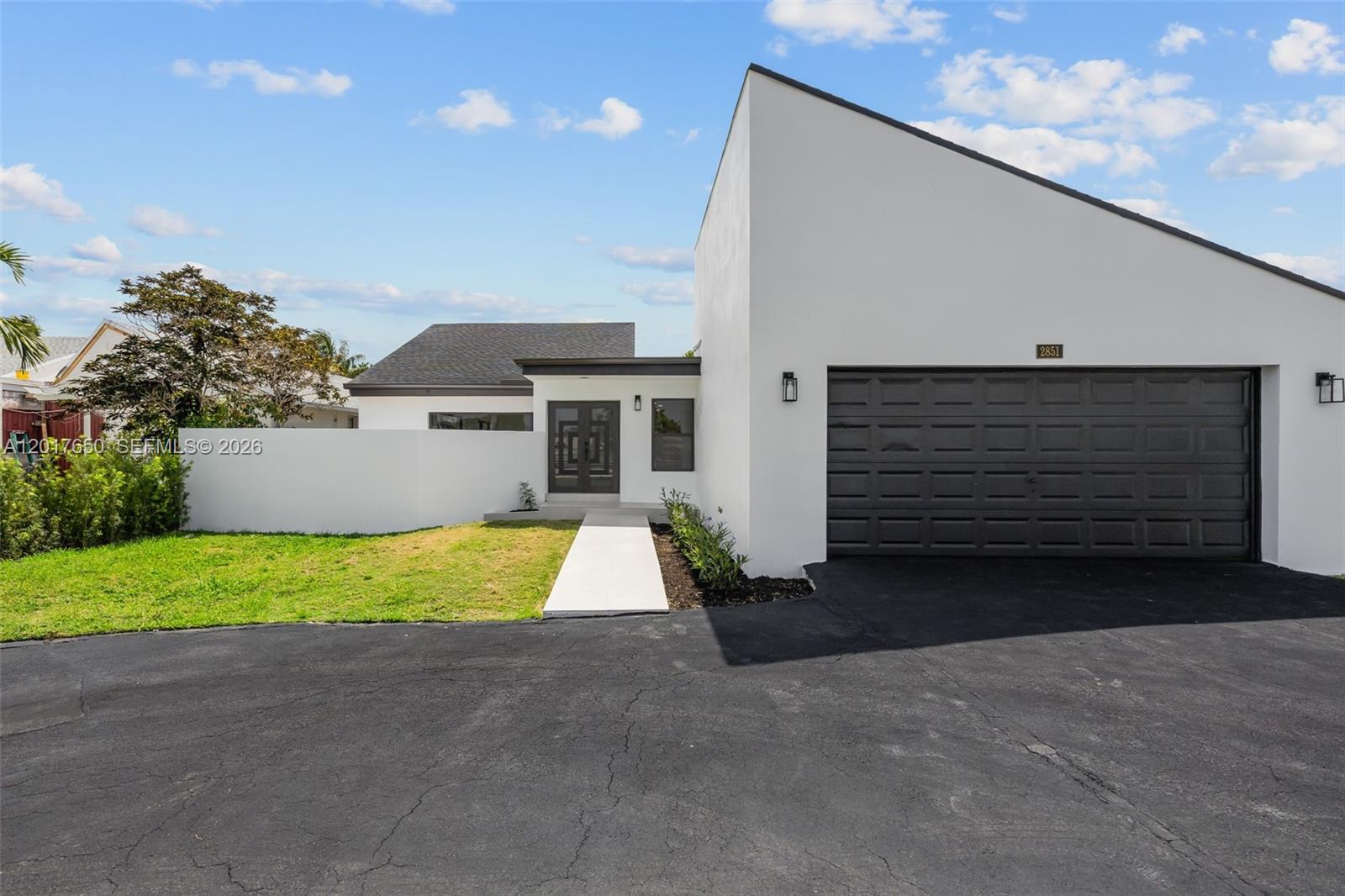 A modern house features a white exterior, a dark garage door, and a paved walkway — 2851 SW 117th Ave, Miami FL 33175, MIAMI, FL