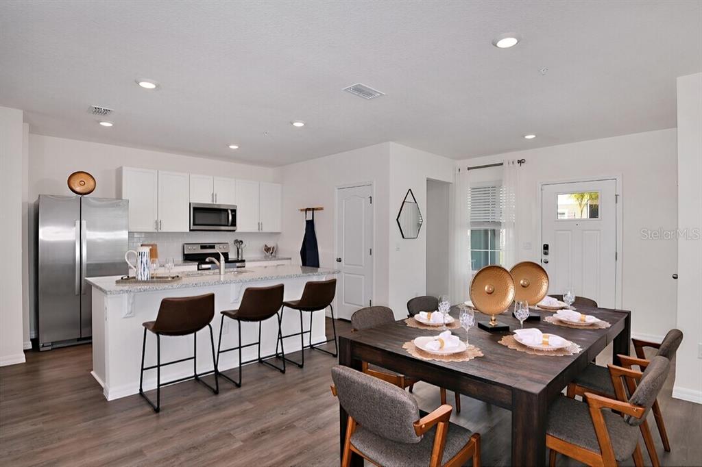A kitchen with white cabinets and an island flows into a dining area with seating — 2607 HARRIER COURT UNIT Eclipse, APOPKA, FL