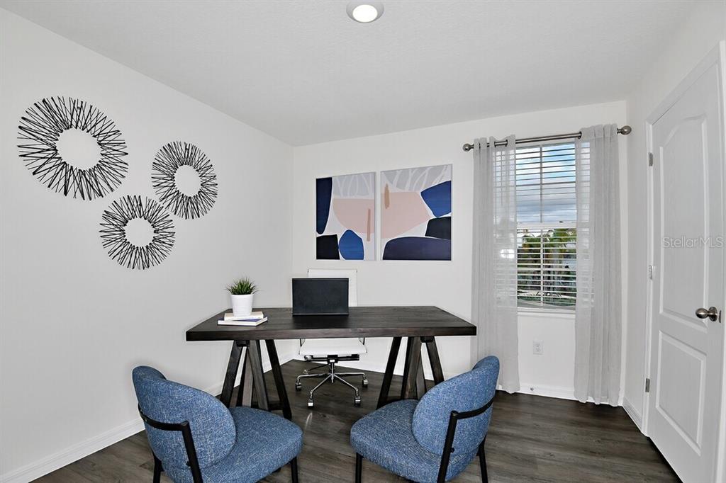 A home office features a dark wood desk, two blue chairs, and abstract wall art — 2607 HARRIER COURT UNIT Eclipse, APOPKA, FL