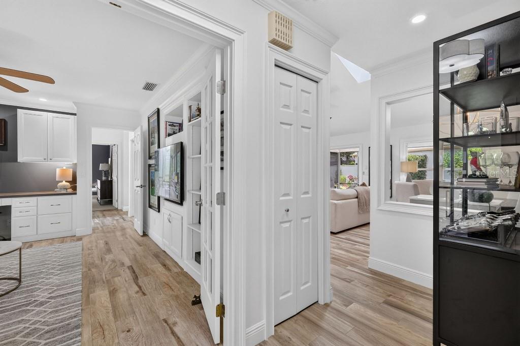 A hallway with white doors, built-in shelving, and light wood flooring leads to other rooms — 4404 NE 4TH STREET, OCALA, FL