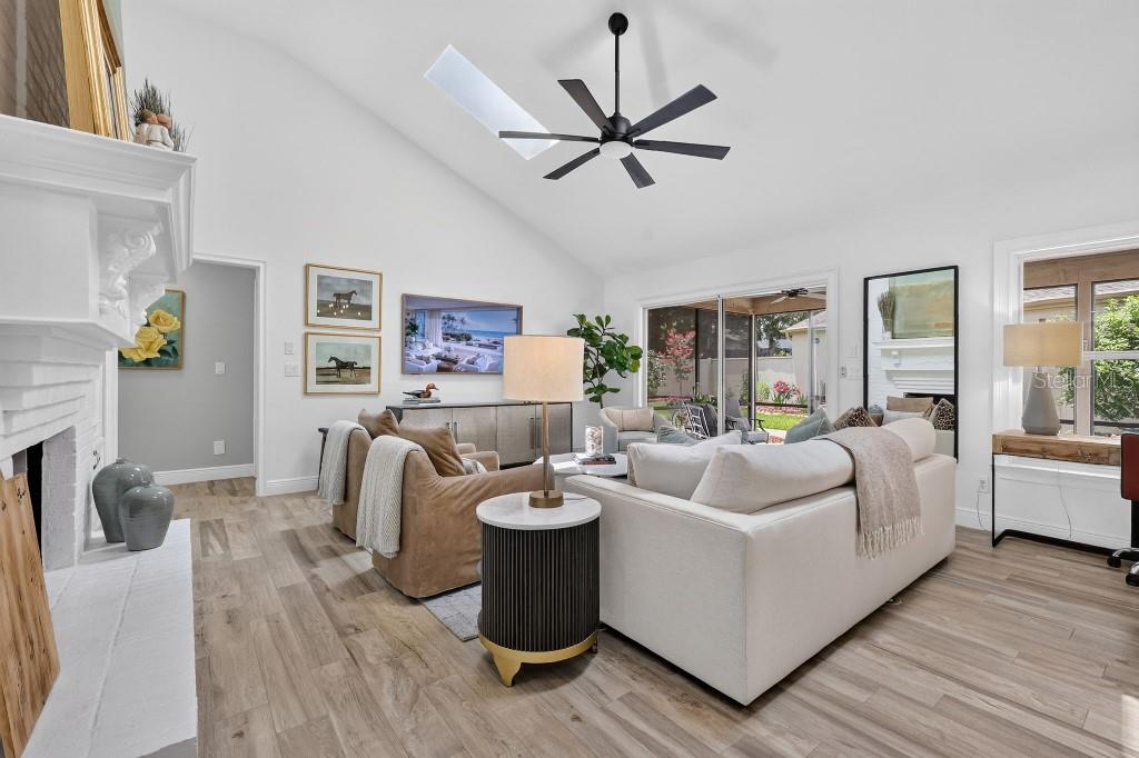 A bright living room features a vaulted ceiling, white fireplace, and neutral furniture — 4404 NE 4TH STREET, OCALA, FL
