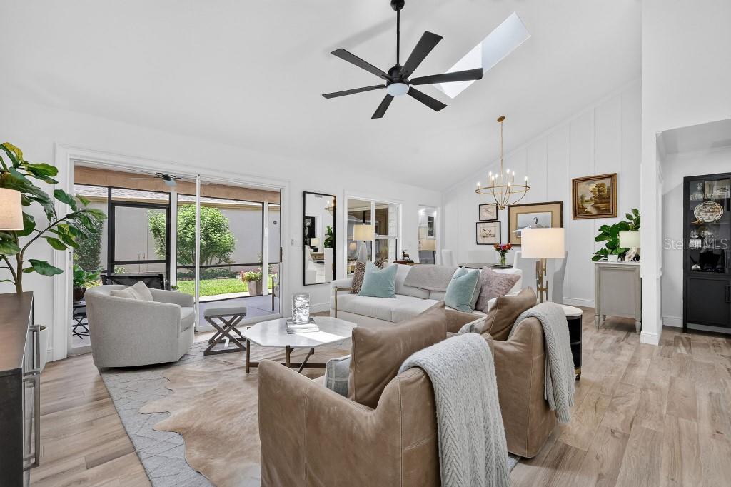 A bright living room features a vaulted ceiling, a ceiling fan, and sliding glass doors — 4404 NE 4TH STREET, OCALA, FL