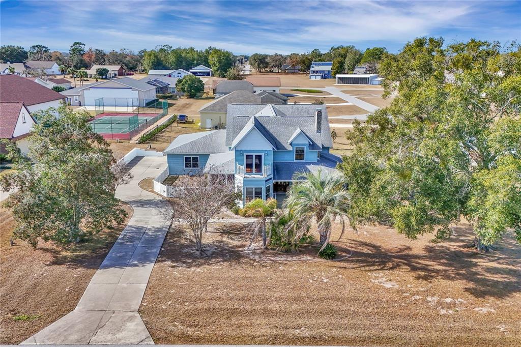 An aerial view shows a blue two-story house with a driveway and surrounding trees — 8900 SE 72ND AVENUE, OCALA, FL