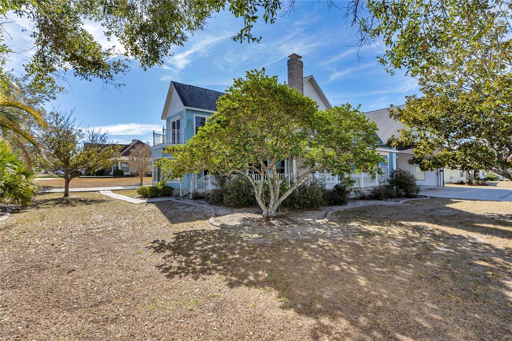 A light blue two-story house with a chimney and a large tree in the yard — 8900 SE 72ND AVENUE, OCALA, FL