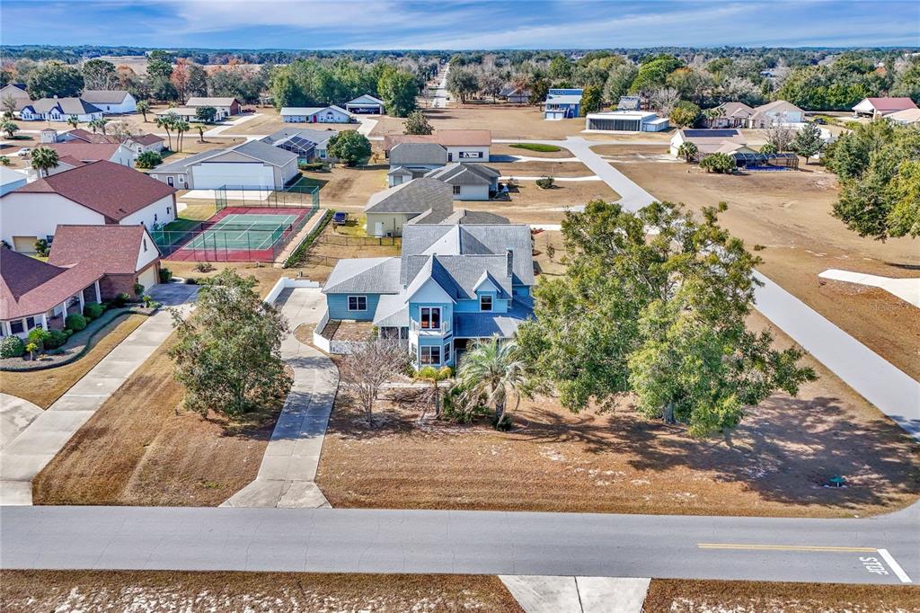 An aerial view shows a blue two-story house with a driveway and surrounding residential properties — 8900 SE 72ND AVENUE, OCALA, FL