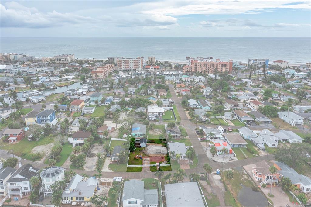 An aerial view shows a residential neighborhood near the ocean with a highlighted vacant lot — 13150 BOCA CIEGA AVENUE, MADEIRA BEACH, FL