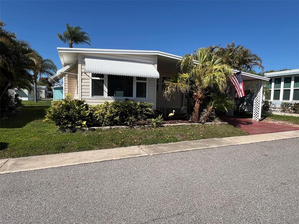 A light-colored mobile home features a white awning, a palm tree, and an American flag — 29250 US HIGHWAY 19 N UNIT 610, CLEARWATER, FL
