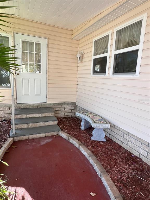 A white door with steps leads to a porch with a bench and siding — 29250 US HIGHWAY 19 N UNIT 610, CLEARWATER, FL