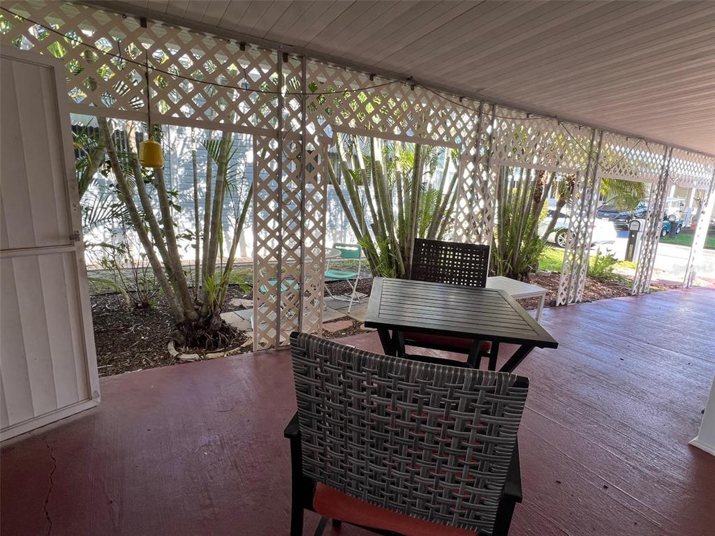 A covered outdoor patio features a dining set, lattice privacy screens, and palm trees — 29250 US HIGHWAY 19 N UNIT 610, CLEARWATER, FL