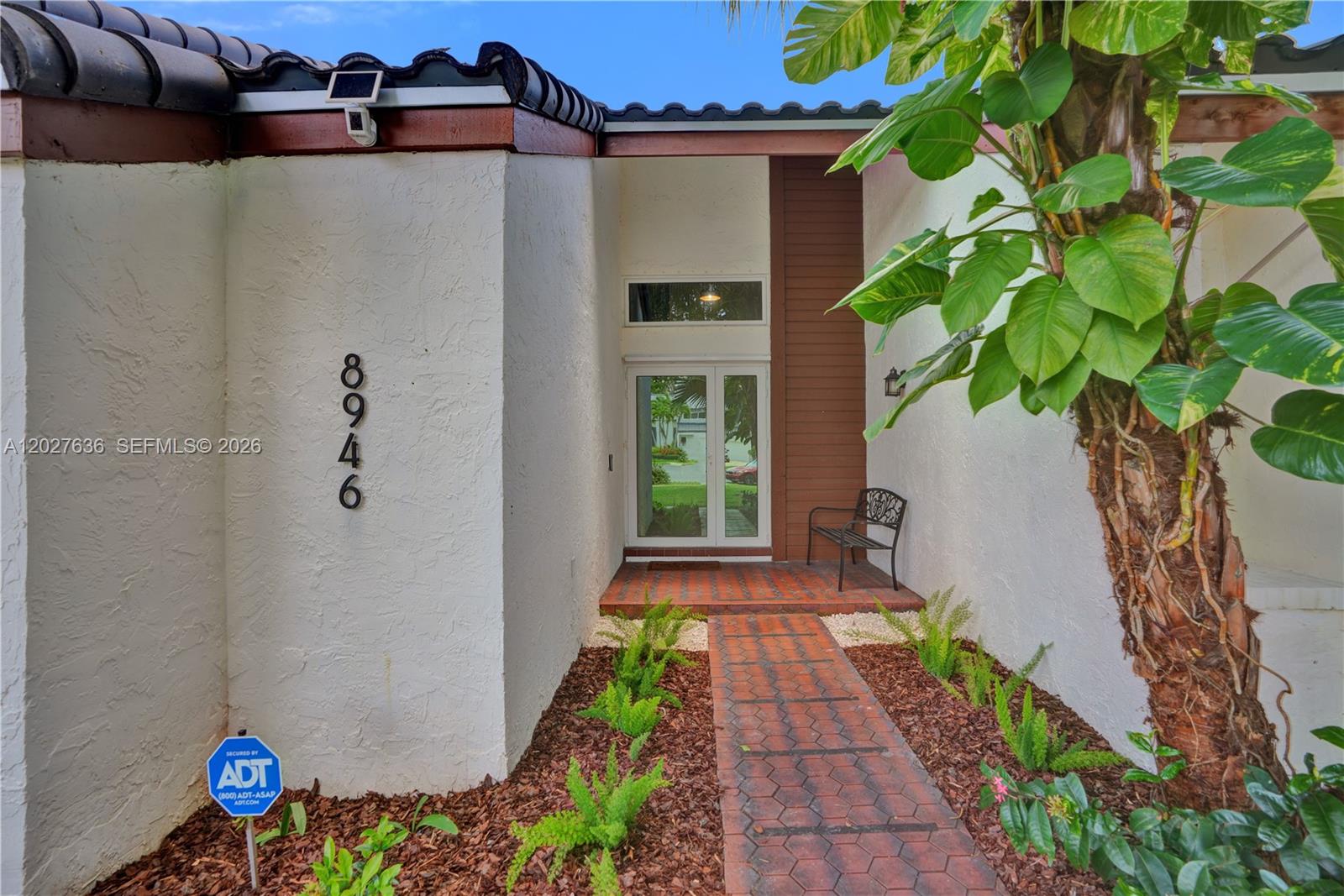 A brick walkway leads to the front entrance of a home with white stucco walls — 8946 SW 150th Ct Cir E, Miami FL 33196, MIAMI, FL