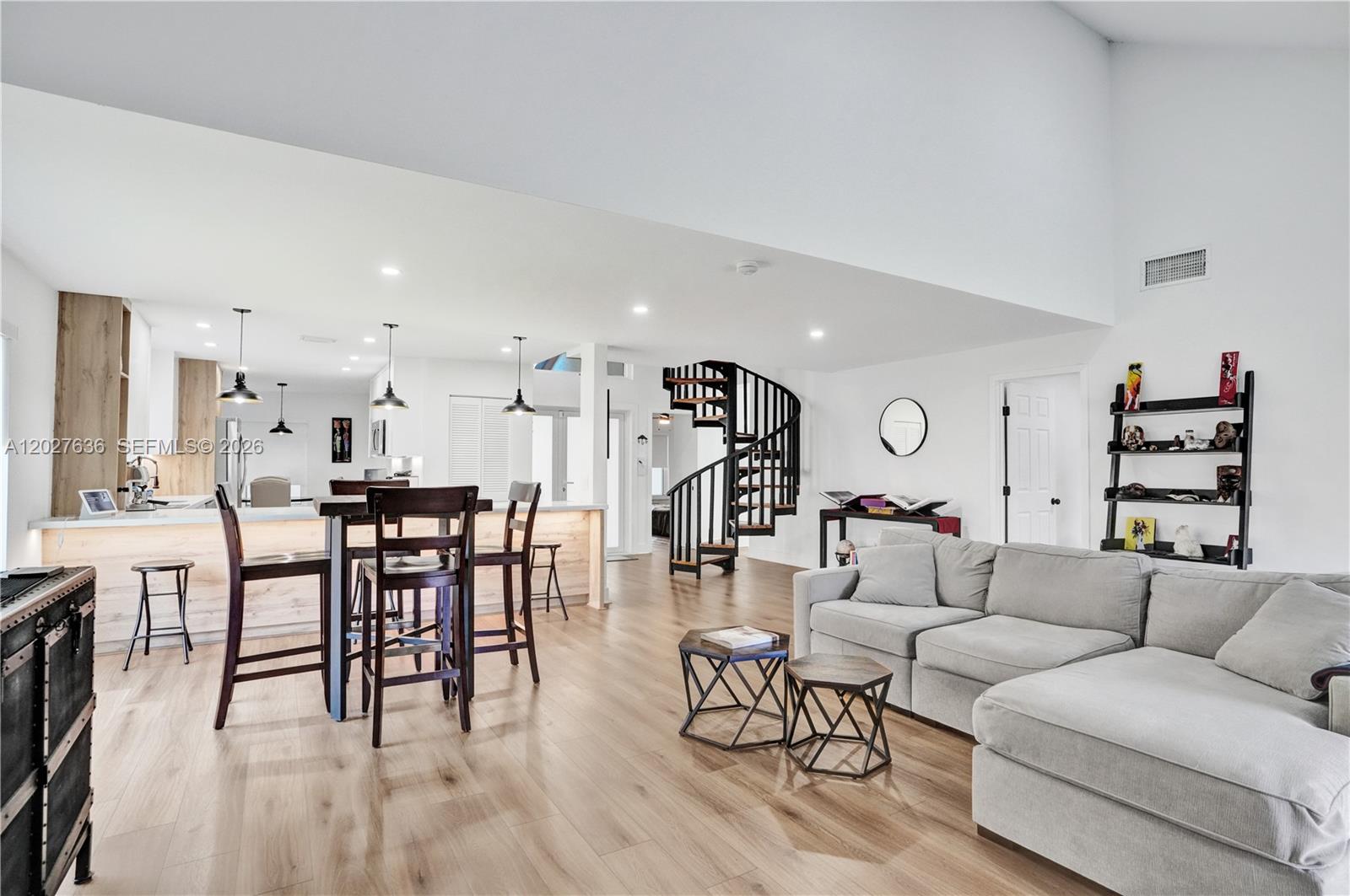 An open-concept living area features a spiral staircase, light wood flooring, and a kitchen island — 8946 SW 150th Ct Cir E, Miami FL 33196, MIAMI, FL