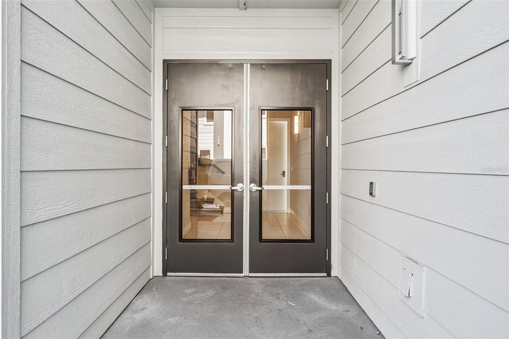 A set of double glass doors with metal frames sits at the entrance of a building — 7760 SANDY RIDGE DRIVE UNIT 112, REUNION, FL