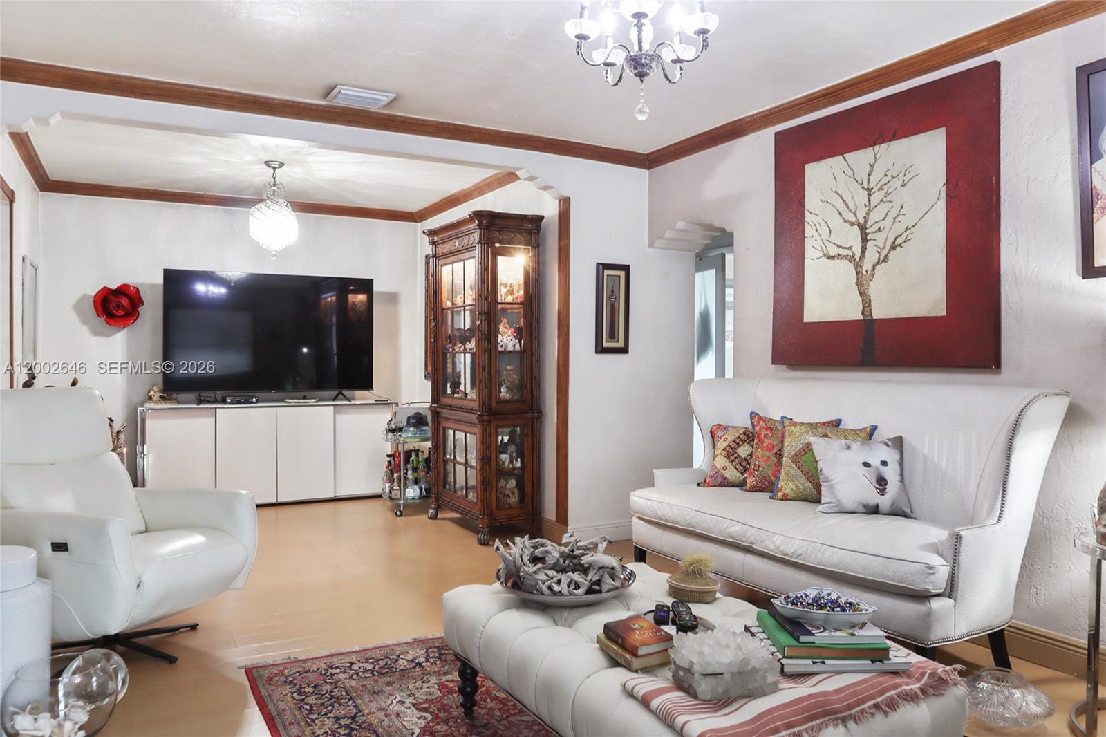 A living room features a white sofa, a tufted ottoman, a television, and a display cabinet — 619 SW 39th Ave, Miami FL 33134, MIAMI, FL