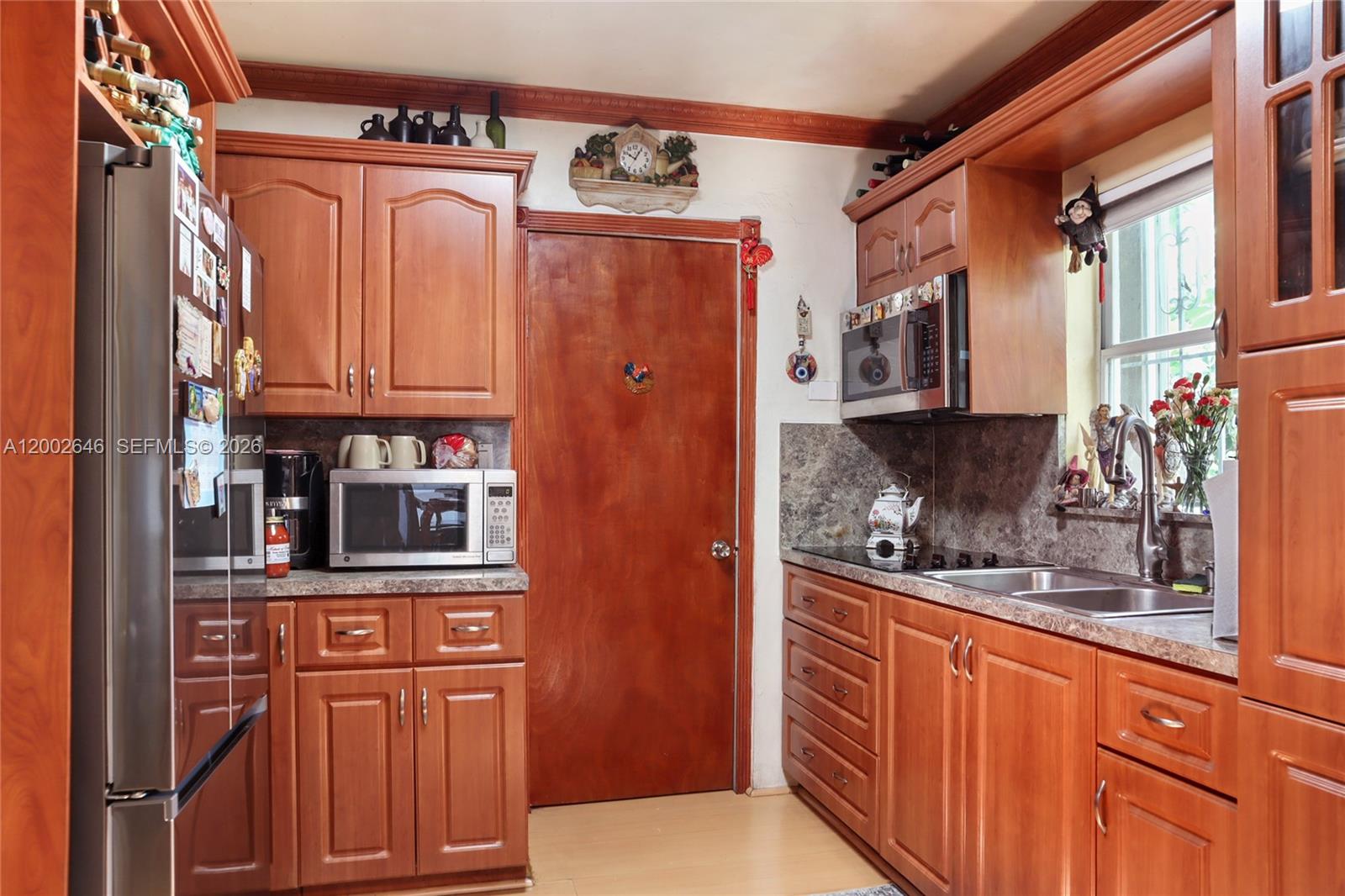 A kitchen features wood cabinets, a stainless steel refrigerator, and a central wooden door — 619 SW 39th Ave, Miami FL 33134, MIAMI, FL
