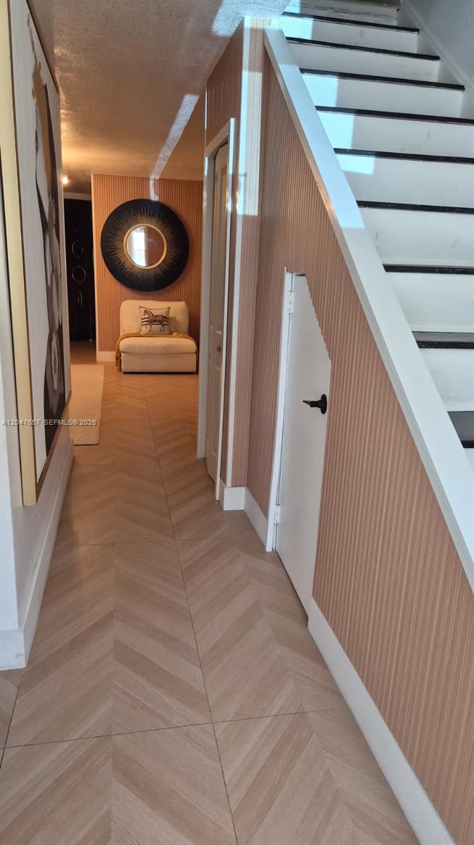 A hallway features herringbone wood-look flooring, vertical-striped wallpaper, and a staircase with white railings — 7190 W 17th Ct, Hialeah FL 33014, HIALEAH, FL