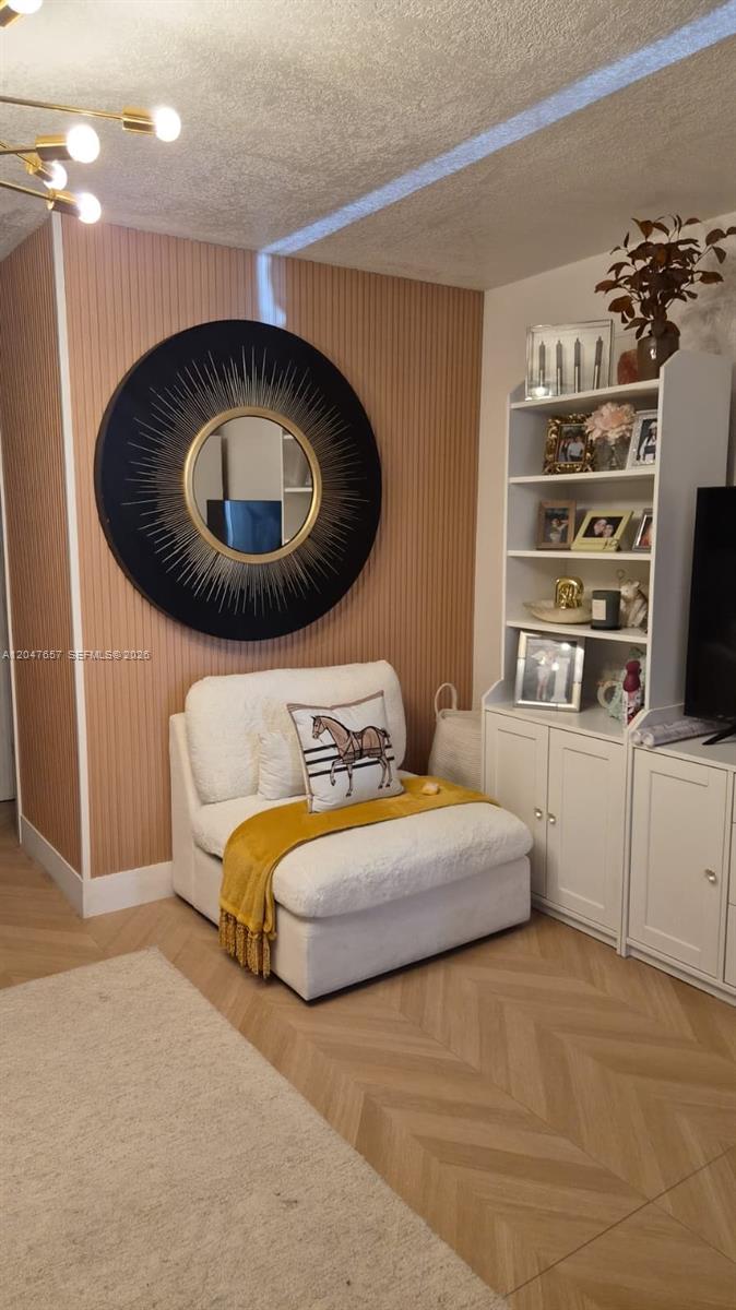 A cozy corner features a white armchair, a round sunburst mirror, and a white bookshelf — 7190 W 17th Ct, Hialeah FL 33014, HIALEAH, FL