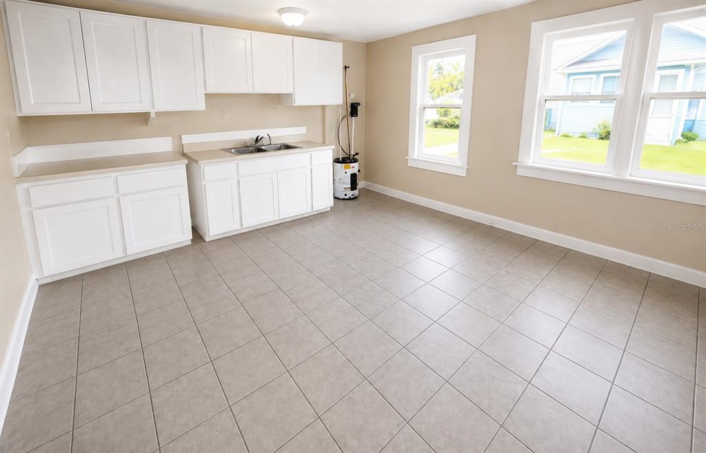 A kitchen with white cabinets, a sink, tile flooring, and two windows — 308 N PENINSULA DRIVE, DAYTONA BEACH, FL