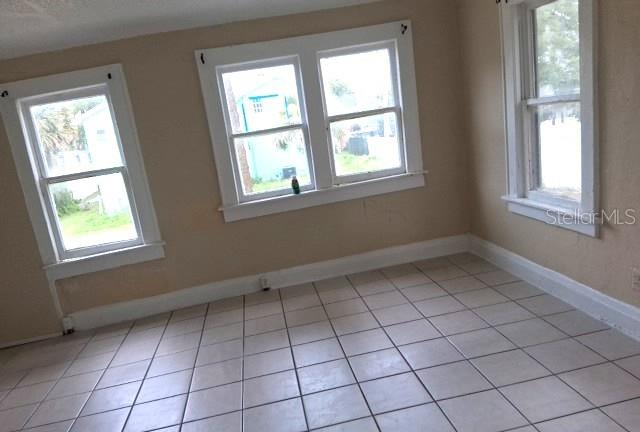 An empty room with light-colored tile flooring and three white-framed windows — 308 N PENINSULA DRIVE, DAYTONA BEACH, FL