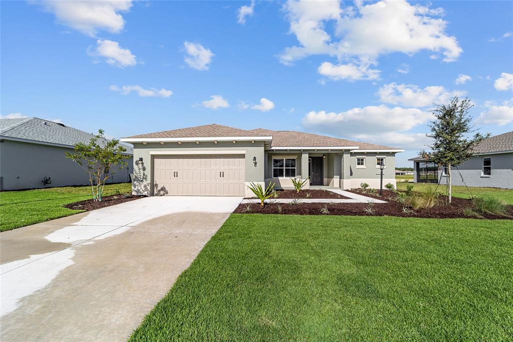 A single-story house with a beige garage, light green exterior, and a concrete driveway — 10372 SW 105TH COURT, OCALA, FL