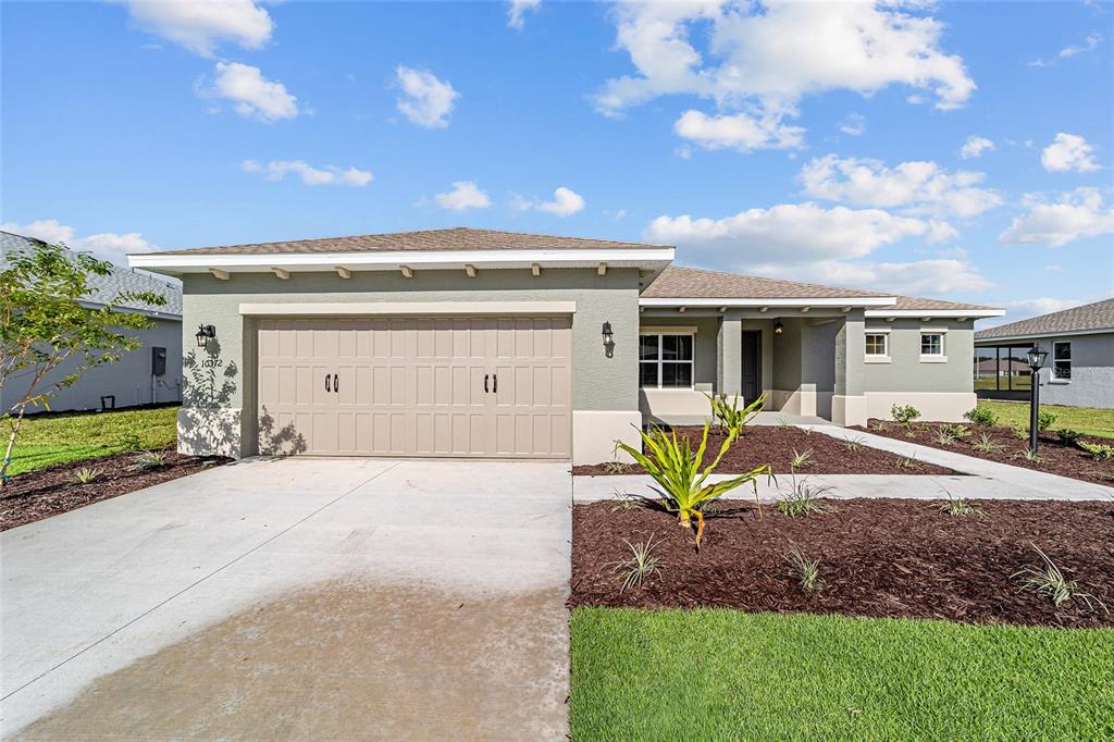 A single-story house with a beige stucco exterior, a two-car garage, and a landscaped yard — 10372 SW 105TH COURT, OCALA, FL