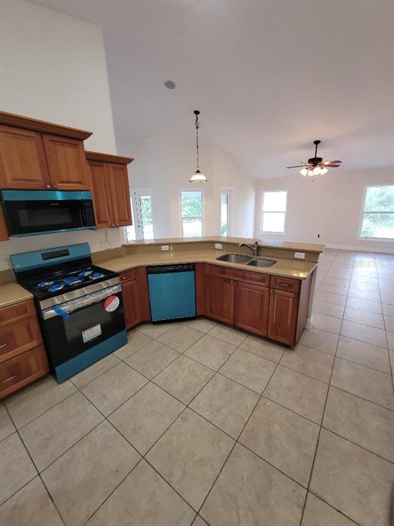A kitchen with wood cabinets, stainless steel appliances, and tile flooring opens to a living area — 1402 JAKWAY ROAD, NORTH PORT, FL