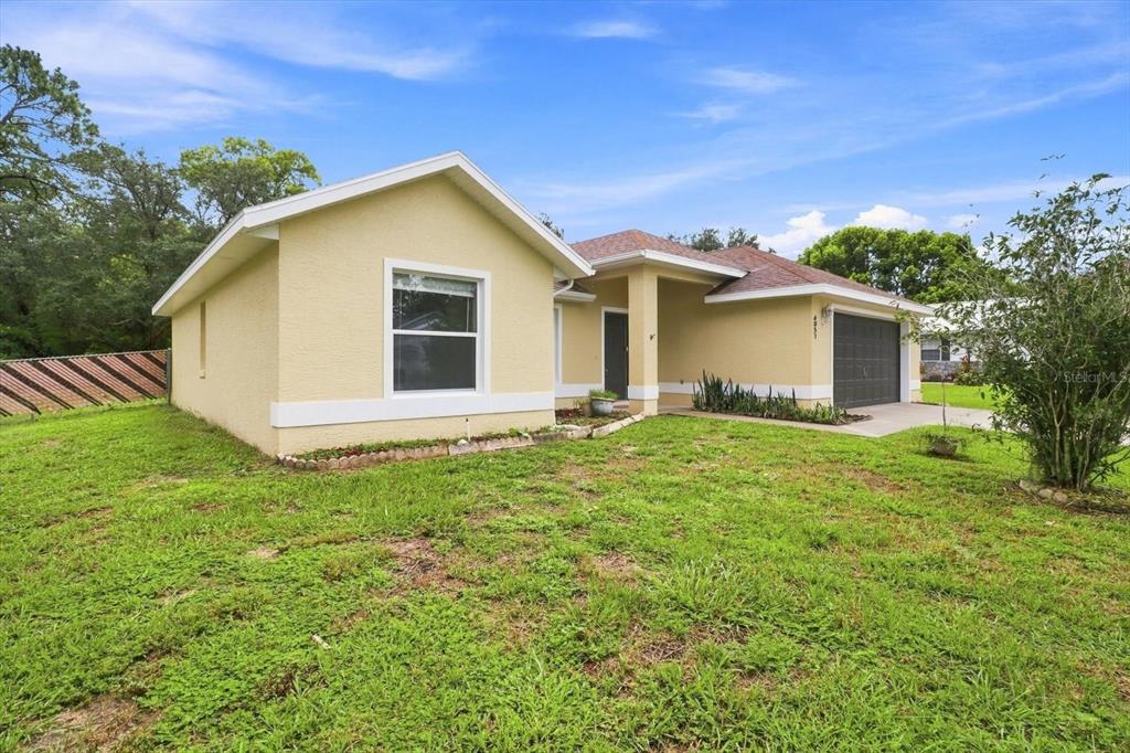 A yellow single-story house with a two-car garage and a grassy front yard — 4051 S WINDING OAKS DRIVE, HOMOSASSA, FL