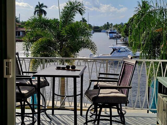A balcony with a table and chairs overlooks a canal with boats and palm trees — 505 N Riverside Drive # 12a, Pompano Beach FL 33062, POMPANO BEACH, FL