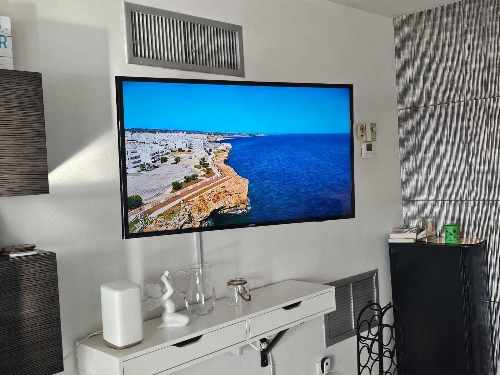 A wall-mounted television displays a coastal landscape above a white floating shelf and console table — 505 N Riverside Drive # 12a, Pompano Beach FL 33062, POMPANO BEACH, FL