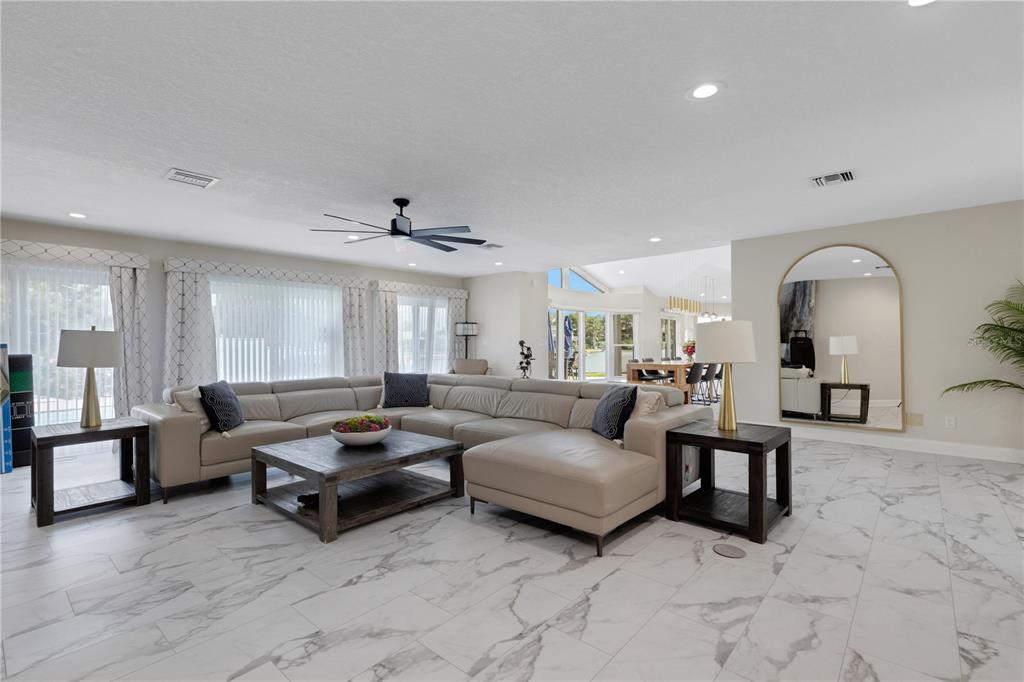 A spacious living room features a large sectional sofa, marble-look tile flooring, and a mirror — 4124 HARBOR CIRCLE S, LARGO, FL