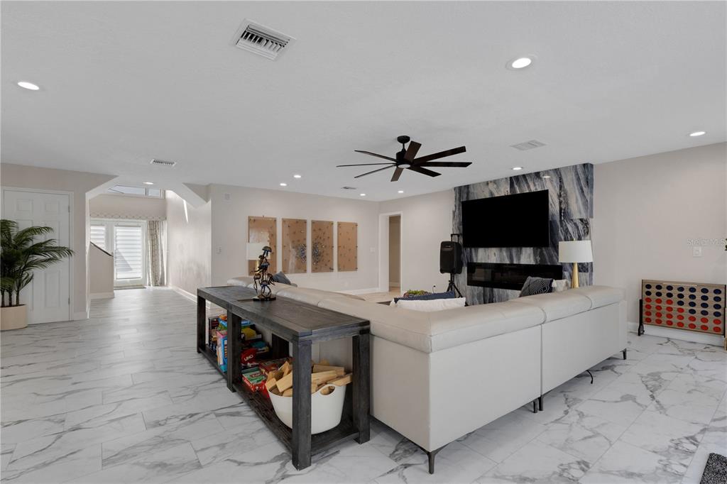A living room features a large sectional sofa, a console table, and a fireplace wall — 4124 HARBOR CIRCLE S, LARGO, FL
