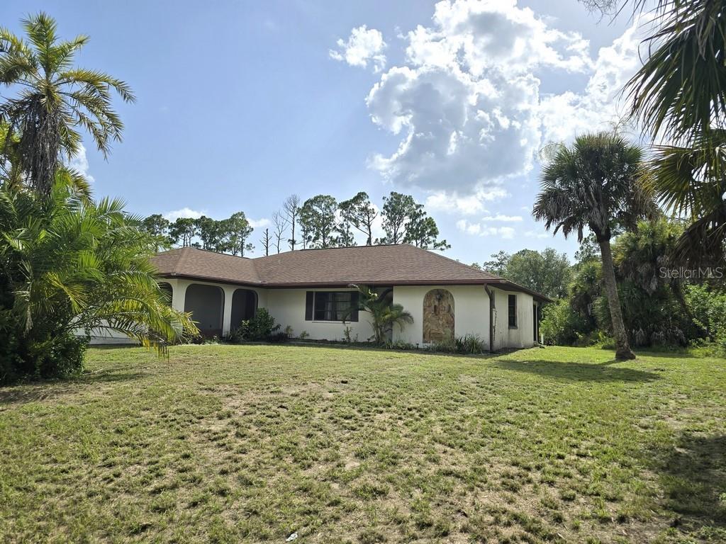 A single-story house with a light-colored exterior and a brown roof sits on a lawn — 279 KINDRED BOULEVARD, PORT CHARLOTTE, FL