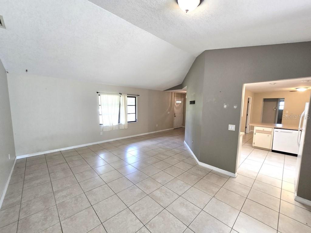 A living room with vaulted ceilings, tile flooring, and an adjacent kitchen area — 279 KINDRED BOULEVARD, PORT CHARLOTTE, FL