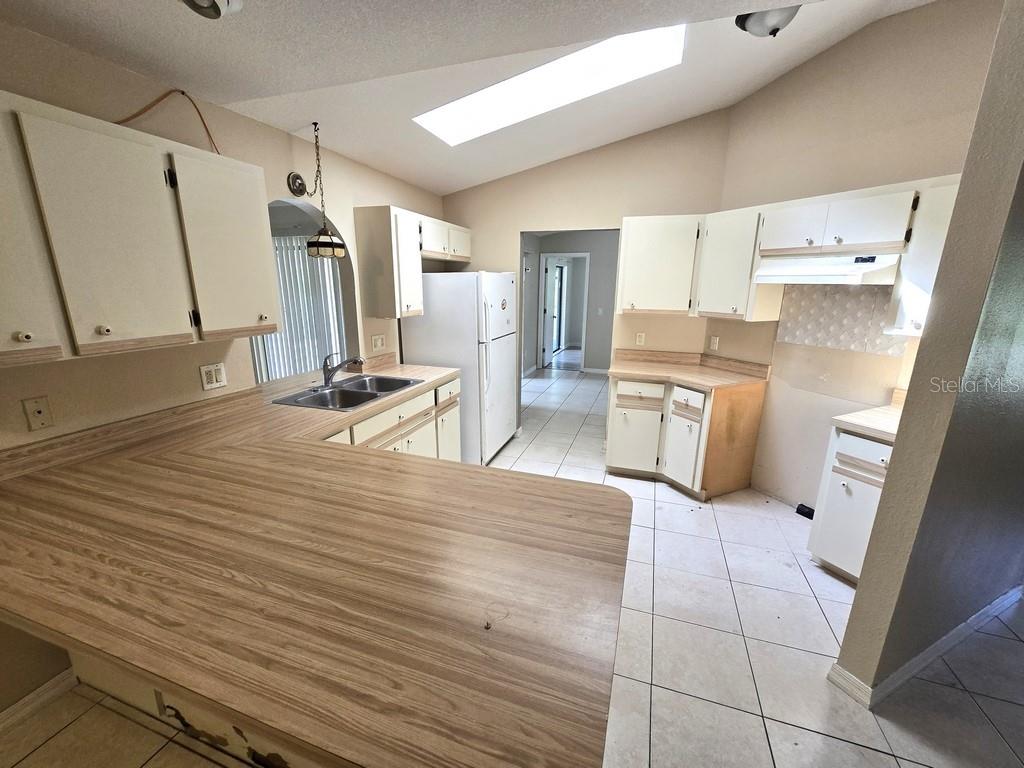 A kitchen with white cabinets, wood-look laminate countertops, tile flooring, and a skylight — 279 KINDRED BOULEVARD, PORT CHARLOTTE, FL