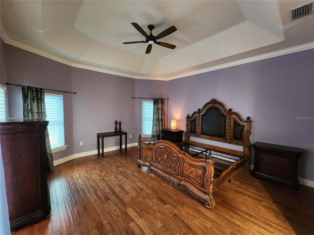A bedroom with purple walls, a tray ceiling, wood flooring, and an ornate wooden bed — 2832 VINTAGE VIEW LOOP, LAKELAND, FL