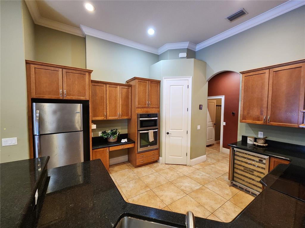 A kitchen features wood cabinets, black granite countertops, stainless steel appliances, and tile flooring — 2832 VINTAGE VIEW LOOP, LAKELAND, FL