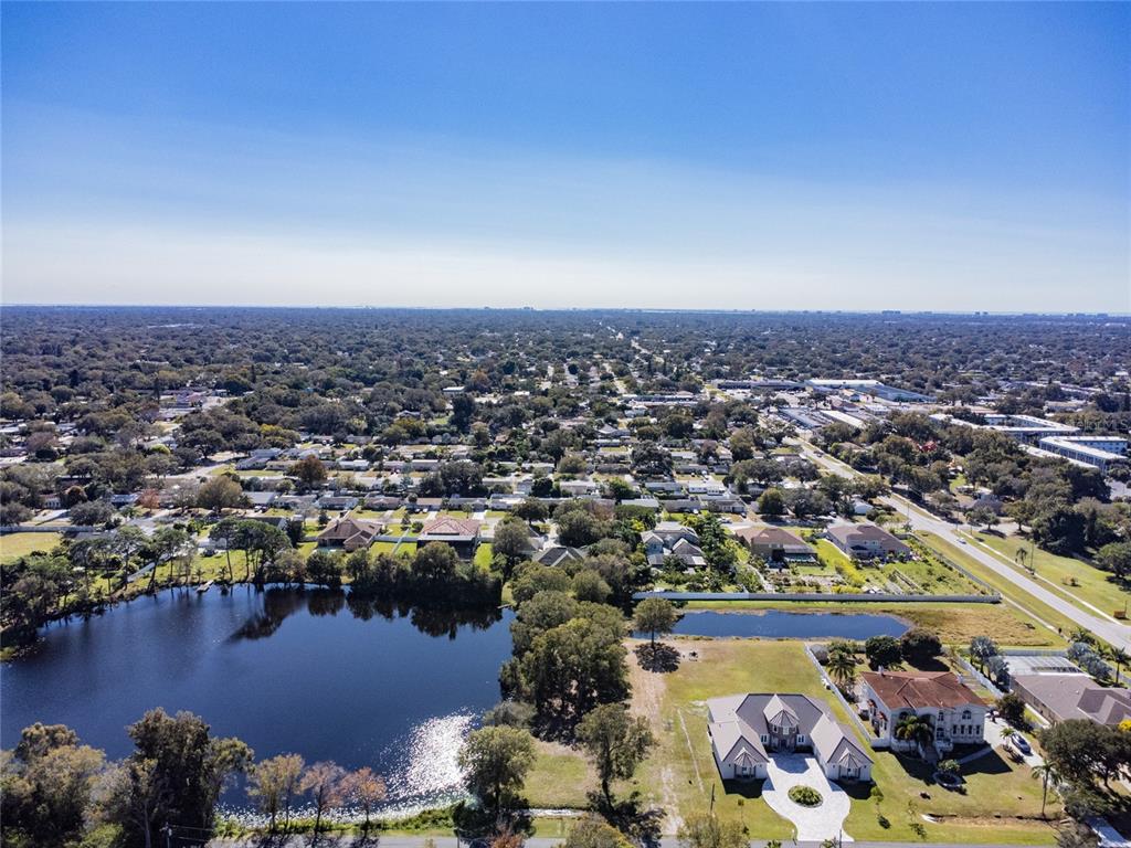 An aerial view shows a suburban neighborhood with two houses near a large pond — 5750 60TH AVENUE N, ST PETERSBURG, FL