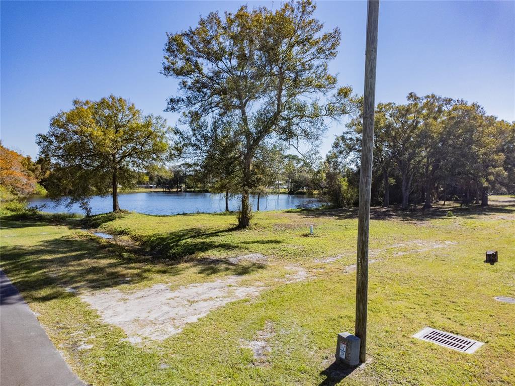 A grassy lot with several trees overlooks a small lake on a sunny day — 5750 60TH AVENUE N, ST PETERSBURG, FL