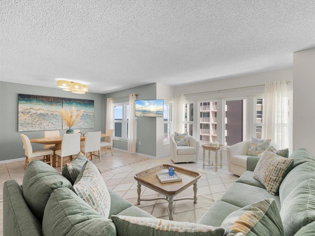 A living and dining room with tile floors, a sectional sofa, and large windows — 17400 GULF BOULEVARD UNIT J7, ST PETERSBURG, FL