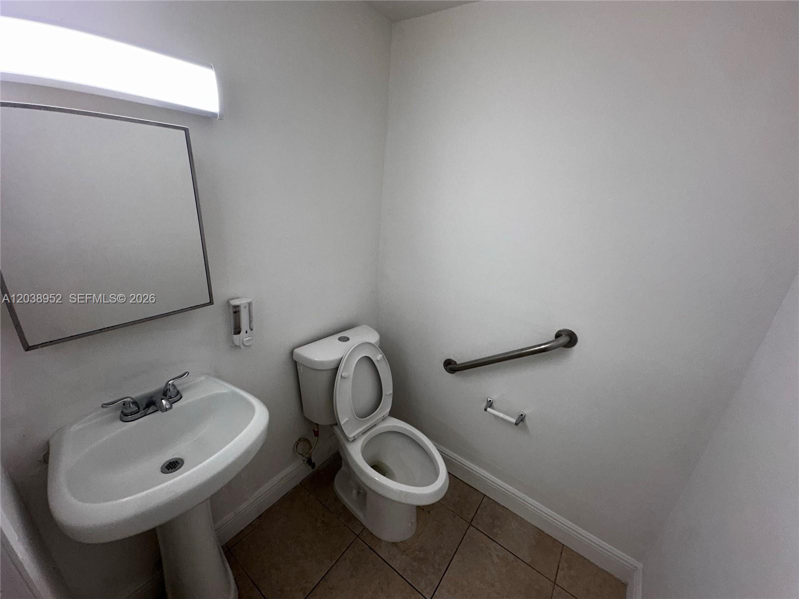 A small bathroom features a pedestal sink, a toilet, and a wall-mounted grab bar — MIAMI, FL