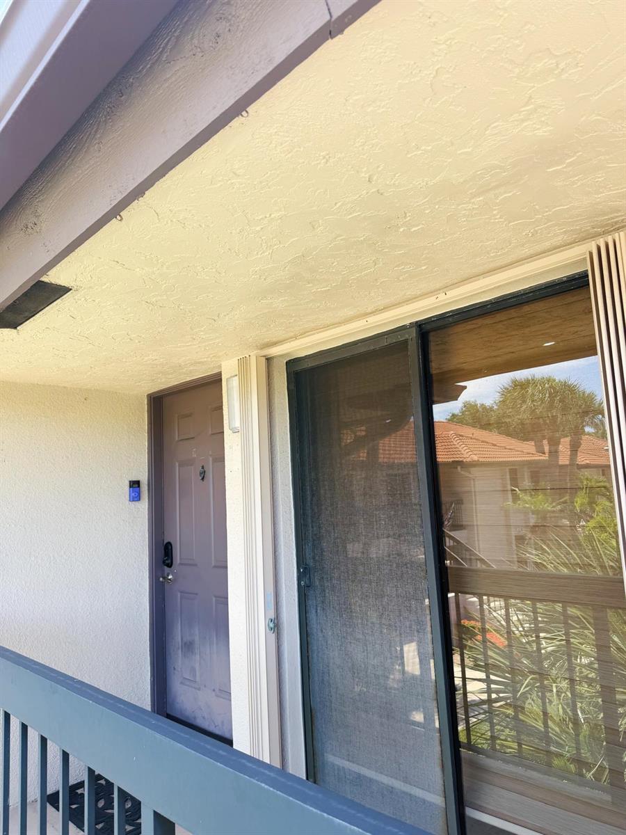 An exterior view of an apartment entrance with a purple door and a sliding glass door — 351 Club Circle # 208, Boca Raton FL 33487, BOCA RATON, FL