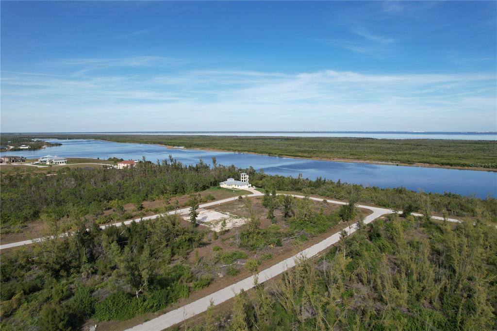 An aerial view shows a house with a tower on a large, wooded waterfront lot — 10565 ABELLO ROAD, PORT CHARLOTTE, FL