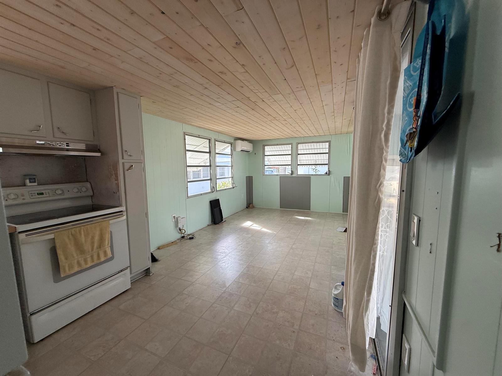 A kitchen and living area features light green walls, a wood-paneled ceiling, and tile flooring — 209 Eagle Drive E, Briny Breezes FL 33435, BRINY BREEZES, FL
