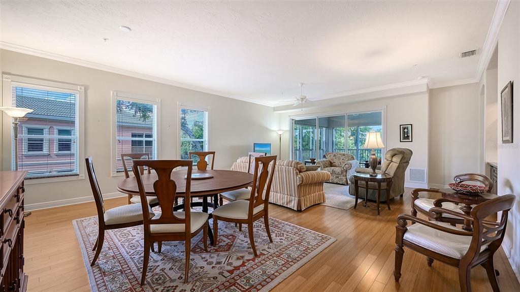 A dining area with a wooden table and chairs sits adjacent to a living room — 5222 MANORWOOD DRIVE UNIT 4A, SARASOTA, FL