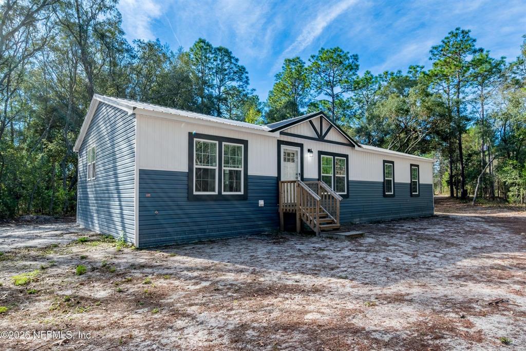 A single-story house with blue and white siding sits on a sandy lot — 7577 HOT SPRINGS COURT, KEYSTONE HEIGHTS, FL