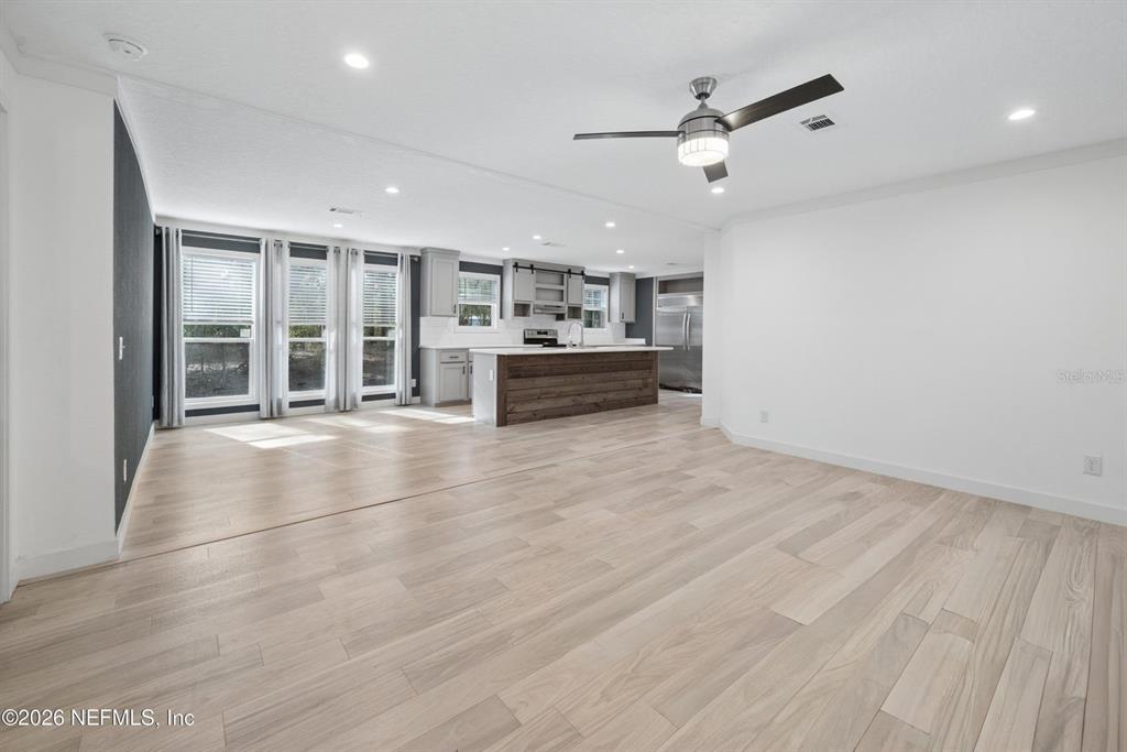 This open-concept kitchen and living area features light wood flooring and a rustic island — 7577 HOT SPRINGS COURT, KEYSTONE HEIGHTS, FL