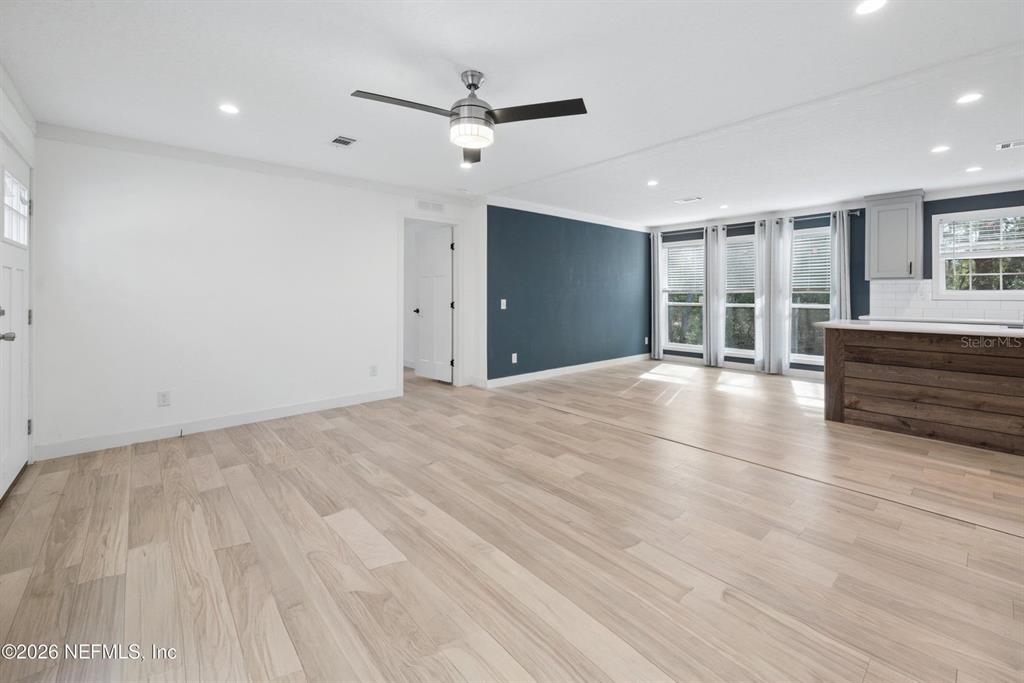 A living room features light wood flooring, a ceiling fan, and a dark blue accent wall — 7577 HOT SPRINGS COURT, KEYSTONE HEIGHTS, FL
