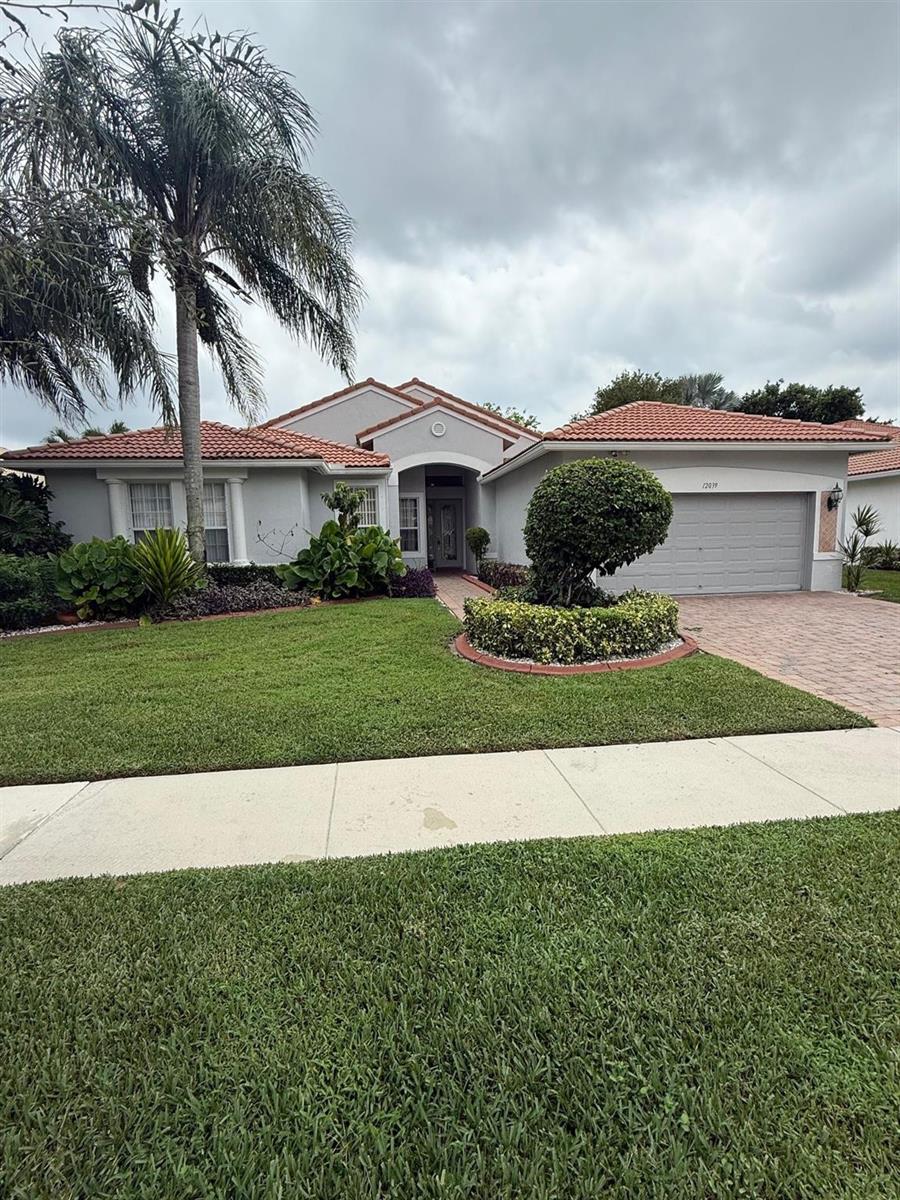 A single-story house with a tiled roof, a two-car garage, and a landscaped front yard — 12039 Oakvista Drive, Boynton Beach FL 33437, BOYNTON BEACH, FL