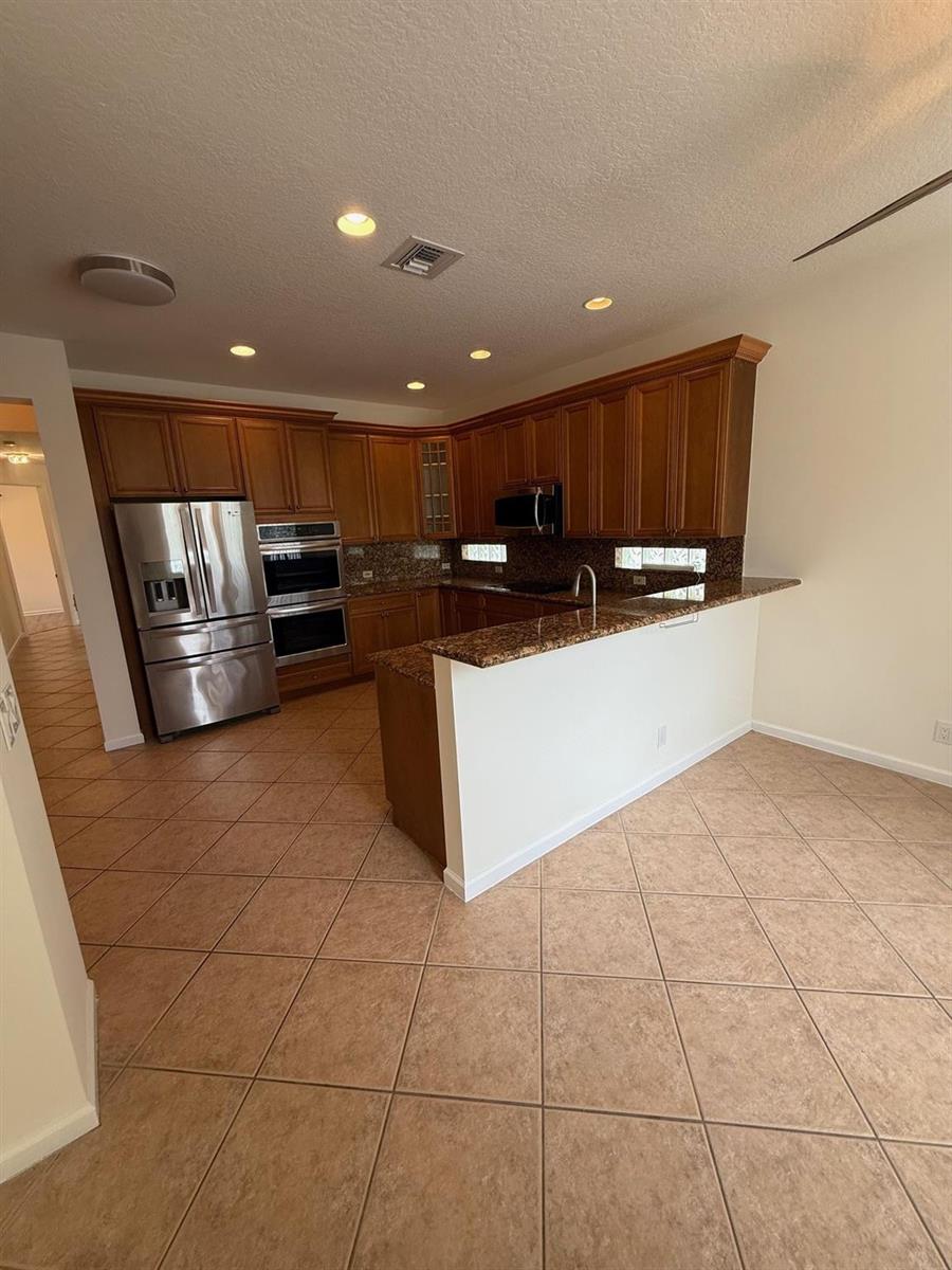 A kitchen with wood cabinets, granite countertops, stainless steel appliances, and diagonal tile flooring — 12039 Oakvista Drive, Boynton Beach FL 33437, BOYNTON BEACH, FL