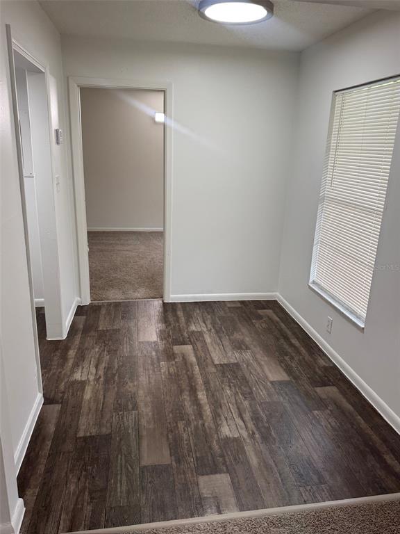 A small room with wood-look flooring, a window with blinds, and a doorway to another room — 1745-1745 NE 2ND STREET UNIT 3, OCALA, FL